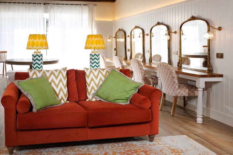 The Tack Barn preparation room: four mirrored hair and make-up stations, a red sofa and panelled walls, Lillibrooke Manor