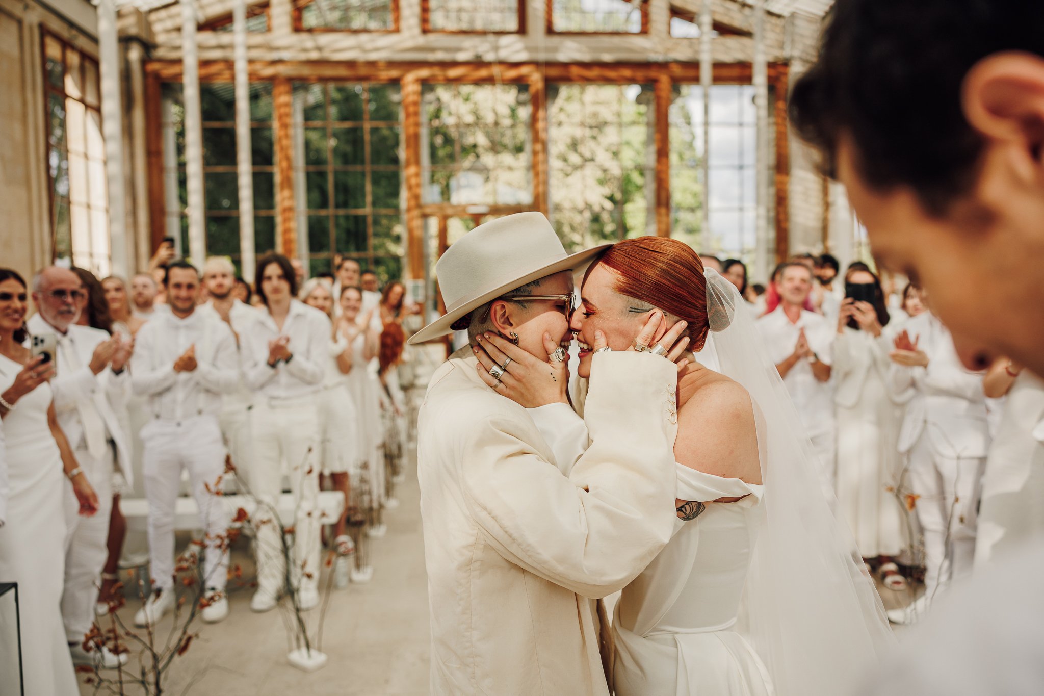 A kiss among guests dressed in white in the Temperate House, Kew Gardens, London, Lina + Tom Photography