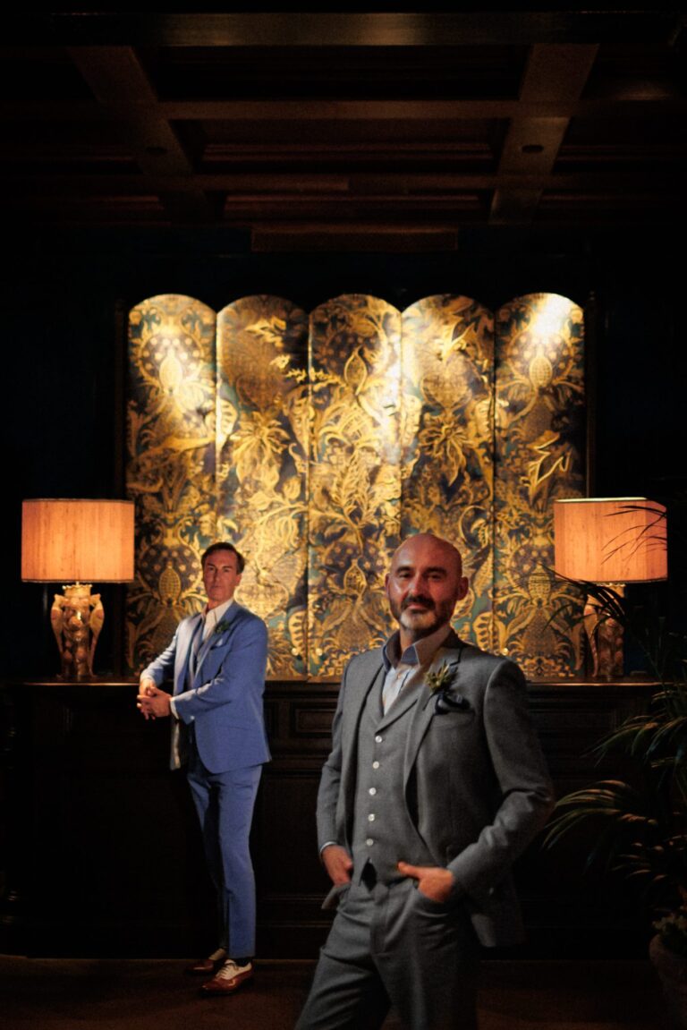 A portrait of two grooms by lamplight against a gilded screen, Lina + Tom Photography