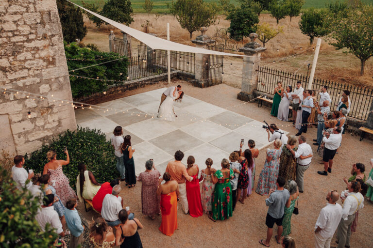 The first dance on an open-air dancefloor, guests gathered around, Chateau Naudou, Lina + Tom Photography