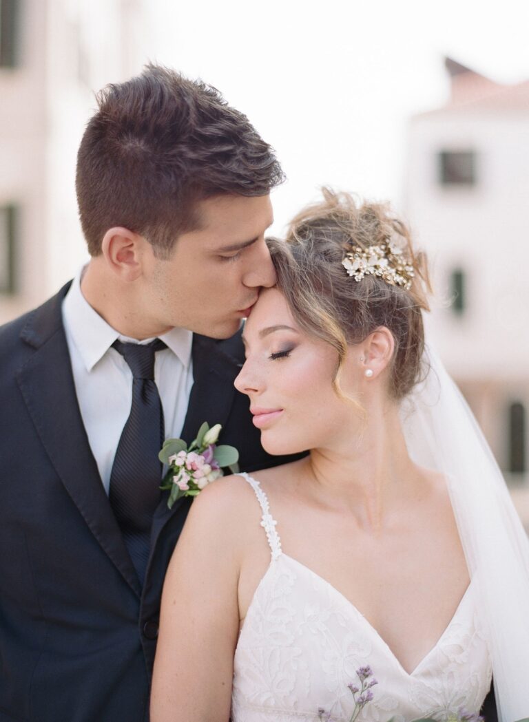 A groom kissing the bride's forehead on a Venice street, Lisa Semenzato