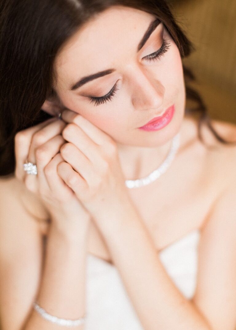 A bride's hand resting near her cheek, ring and pearl necklace visible, Lisa Semenzato