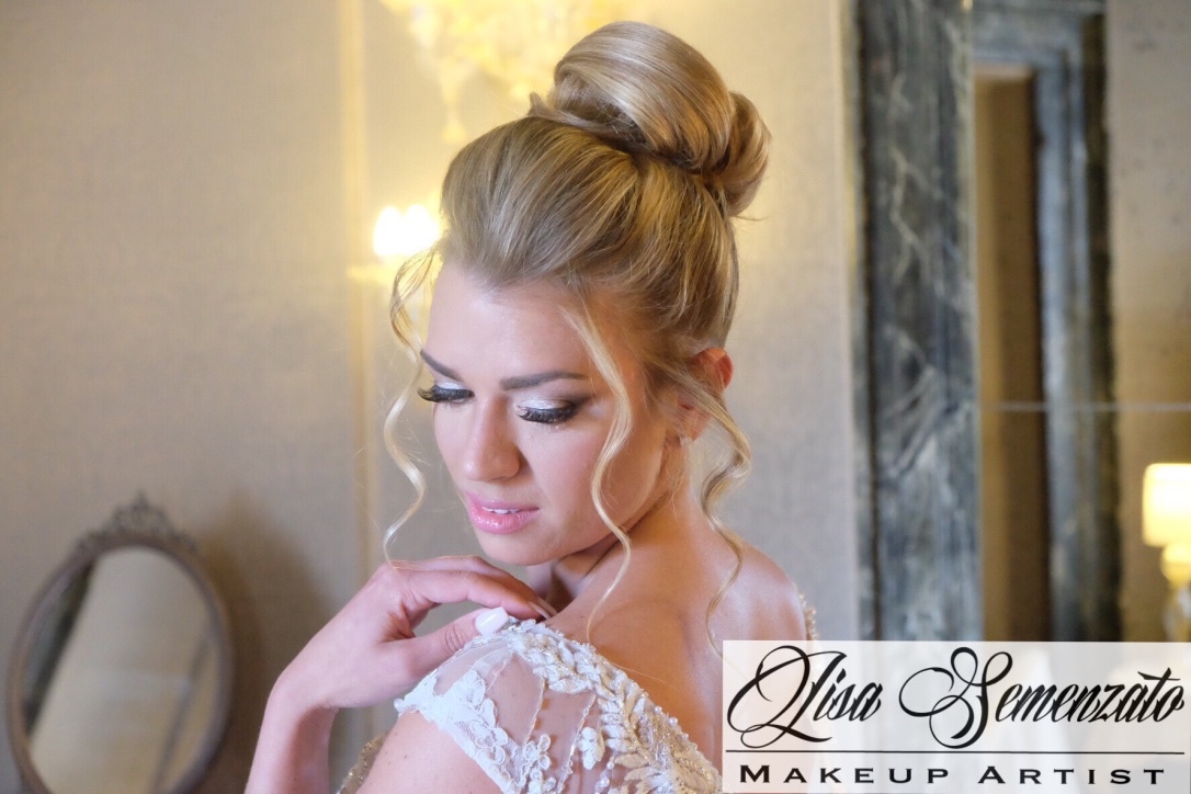 A blonde bride in a sleek high bun, glancing over her shoulder, Lisa Semenzato