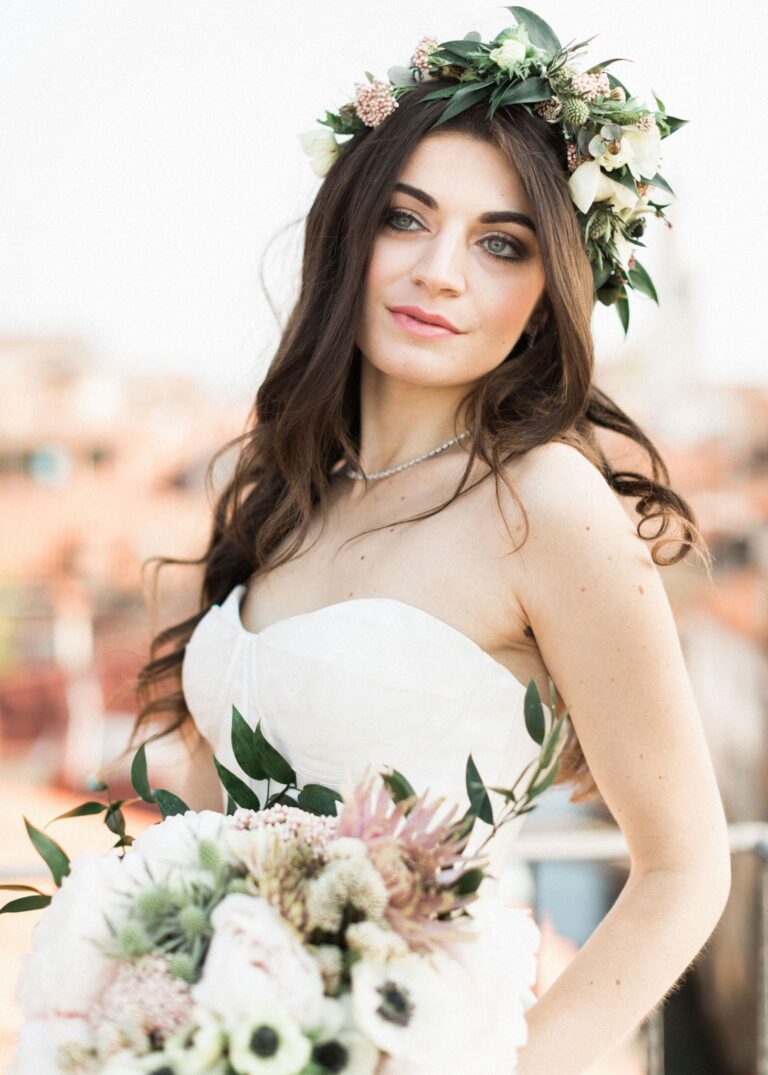 A bride with a fresh floral crown, holding a bouquet on a Venice rooftop, Lisa Semenzato