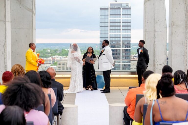 Ceremony on a rooftop terrace with the Nashville skyline behind the couple and their officiant, Living Ceremonies