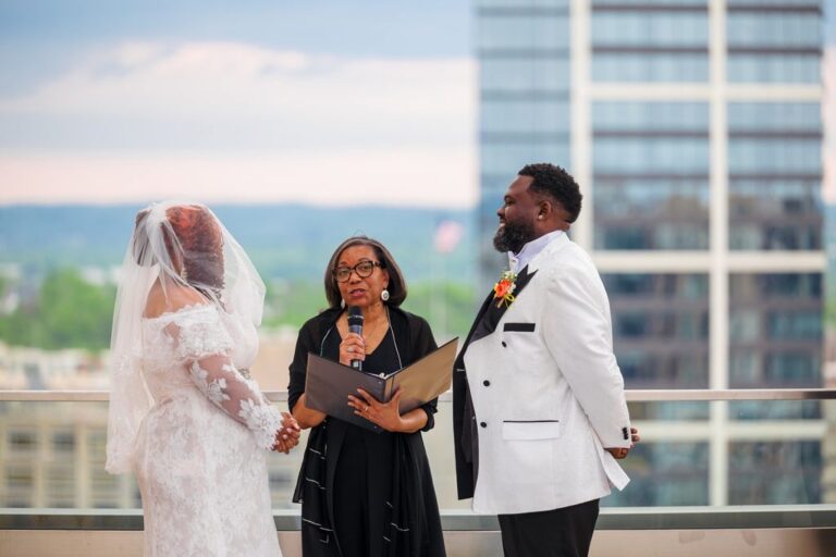 The officiant reads to a couple at a rooftop ceremony above the city, Living Ceremonies