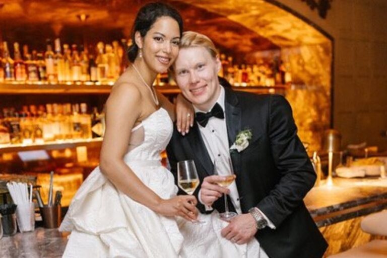 A couple with champagne in front of a warmly lit bar, Living Ceremonies