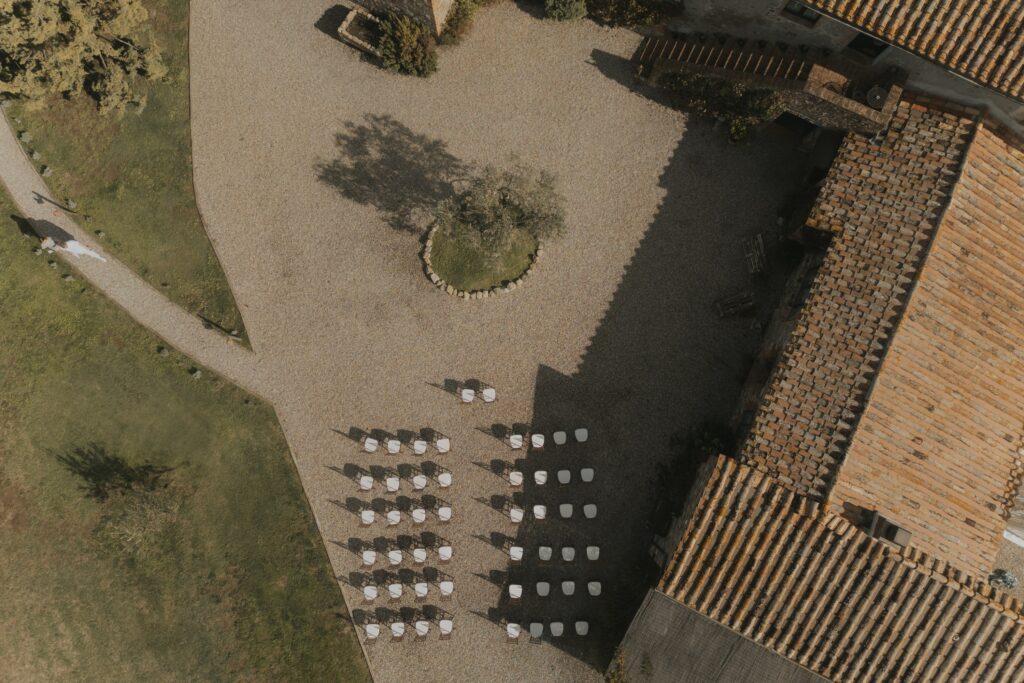 Ceremony chairs set out beside the terracotta-tiled roof, seen from above, Locanda in Tuscany