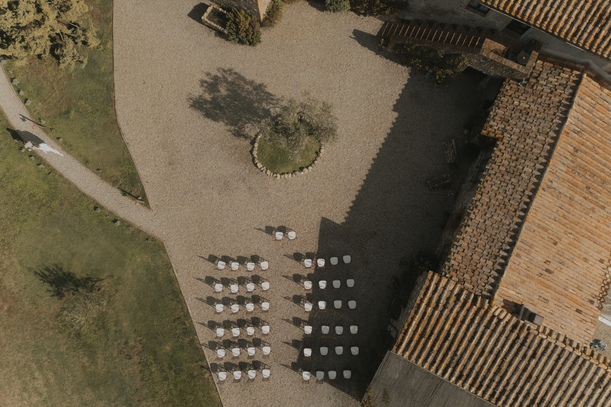 Ceremony chairs set out beside the terracotta-tiled roof, seen from above, Locanda in Tuscany
