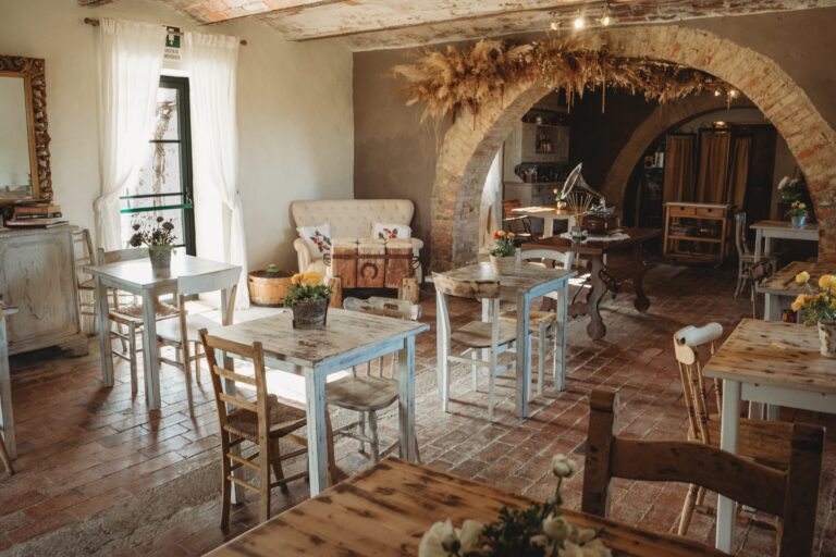 The stone-arched dining room with tables set, Locanda in Tuscany