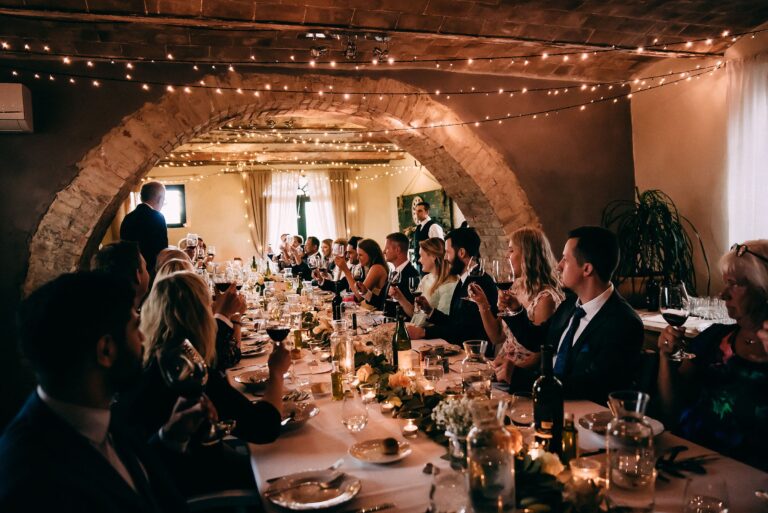 A wedding dinner in the stone-arched room, hung with festoon lights, Locanda in Tuscany
