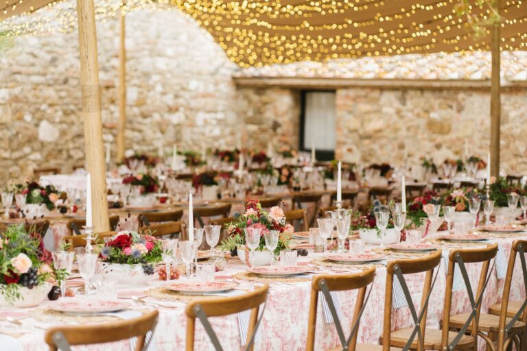 Tables set with flowers in the stone barn, lit with festoon lights, Locanda in Tuscany