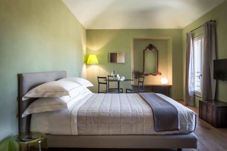 A bedroom with green walls, a large bed and a mirror, Locanda La Raia