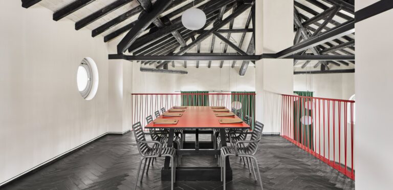 A long table in a high room with timber beams and a red balustrade, Locanda La Raia