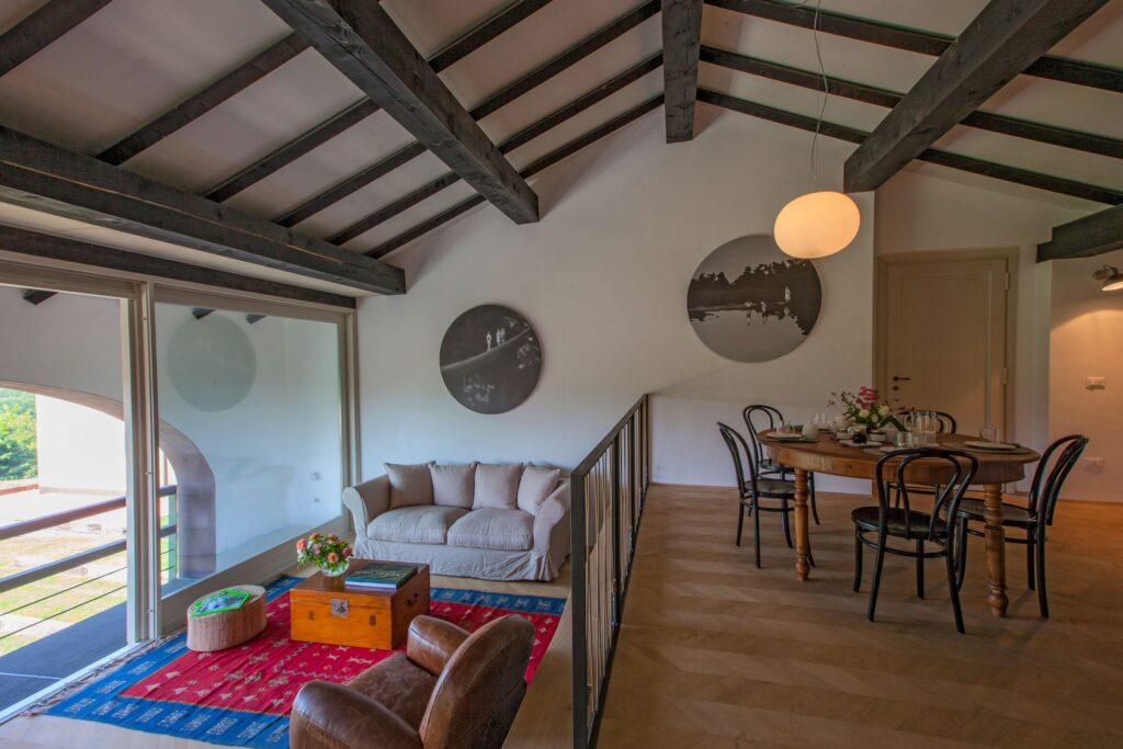 A timber-beamed living and dining space with a gallery rail, Locanda La Raia