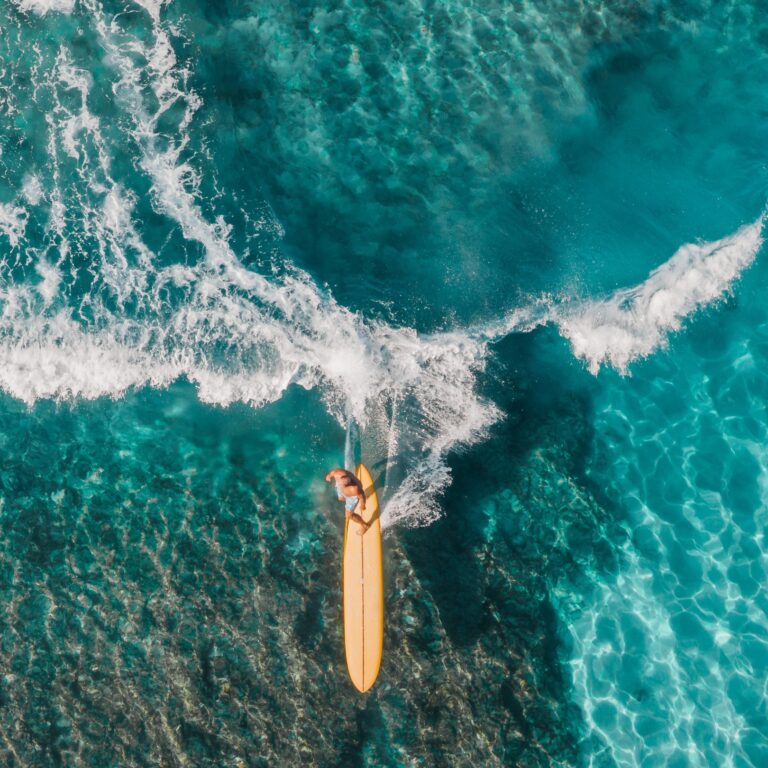 Surfer riding a wave, seen from above, Long Bay Beach Resort