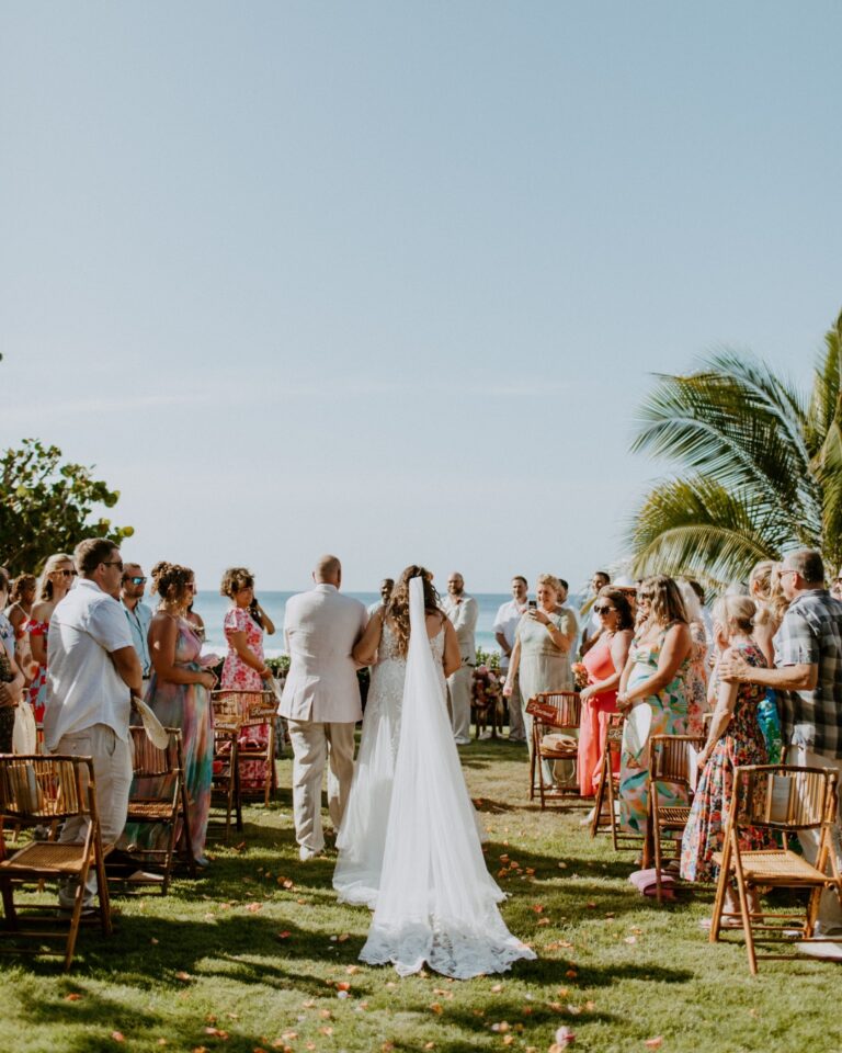 Ceremony on the lawn, with guests seated in white chairs, Long Bay Beach Resort