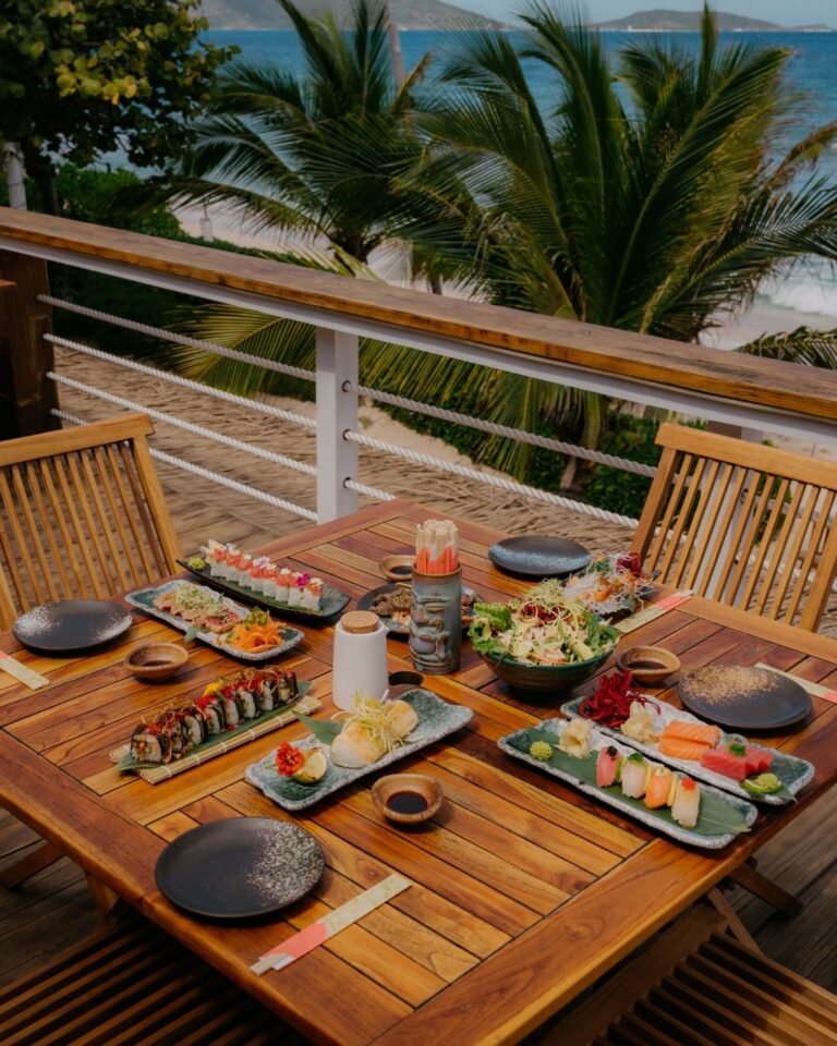 Sushi and dishes on a timber table outdoors, Long Bay Beach Resort