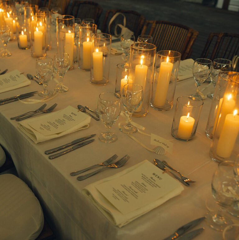 Candlelit dinner table set with linen and glassware, Long Bay Beach Resort