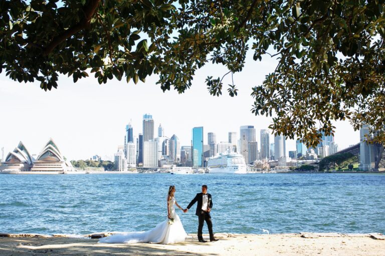 A couple walk hand in hand, Sydney's skyline through the trees, Lorella Giannini