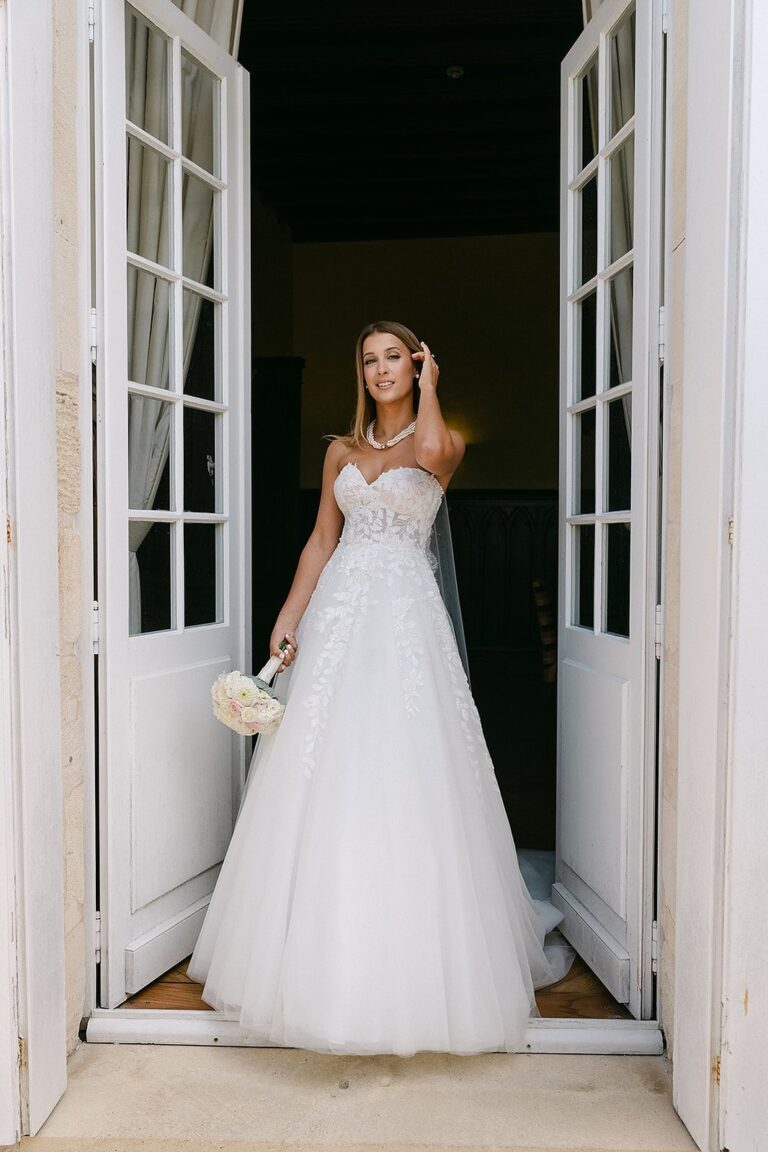 A bride alone in a doorway, bouquet in hand, Lorella Giannini