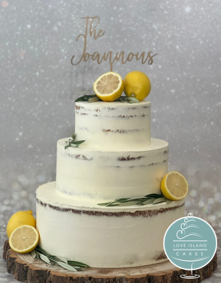 A three-tier semi-naked cake with lemons and olive sprigs on a wooden slice with a personalised topper, Love Island Cakes