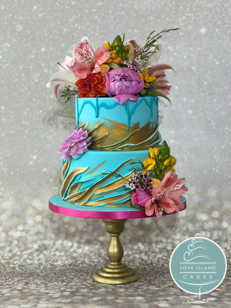 A turquoise and gold brushstroke cake topped with bright pink and orange flowers, Love Island Cakes