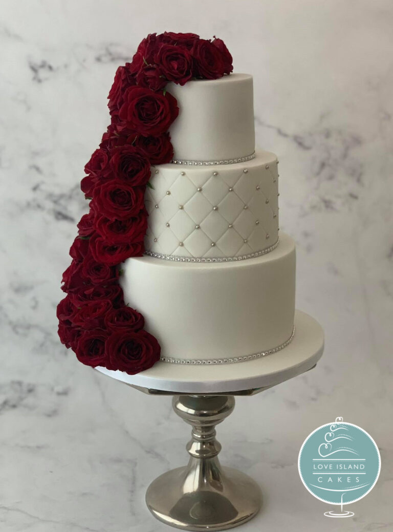A three-tier white cake with a quilted middle tier and a cascade of deep burgundy roses, Love Island Cakes