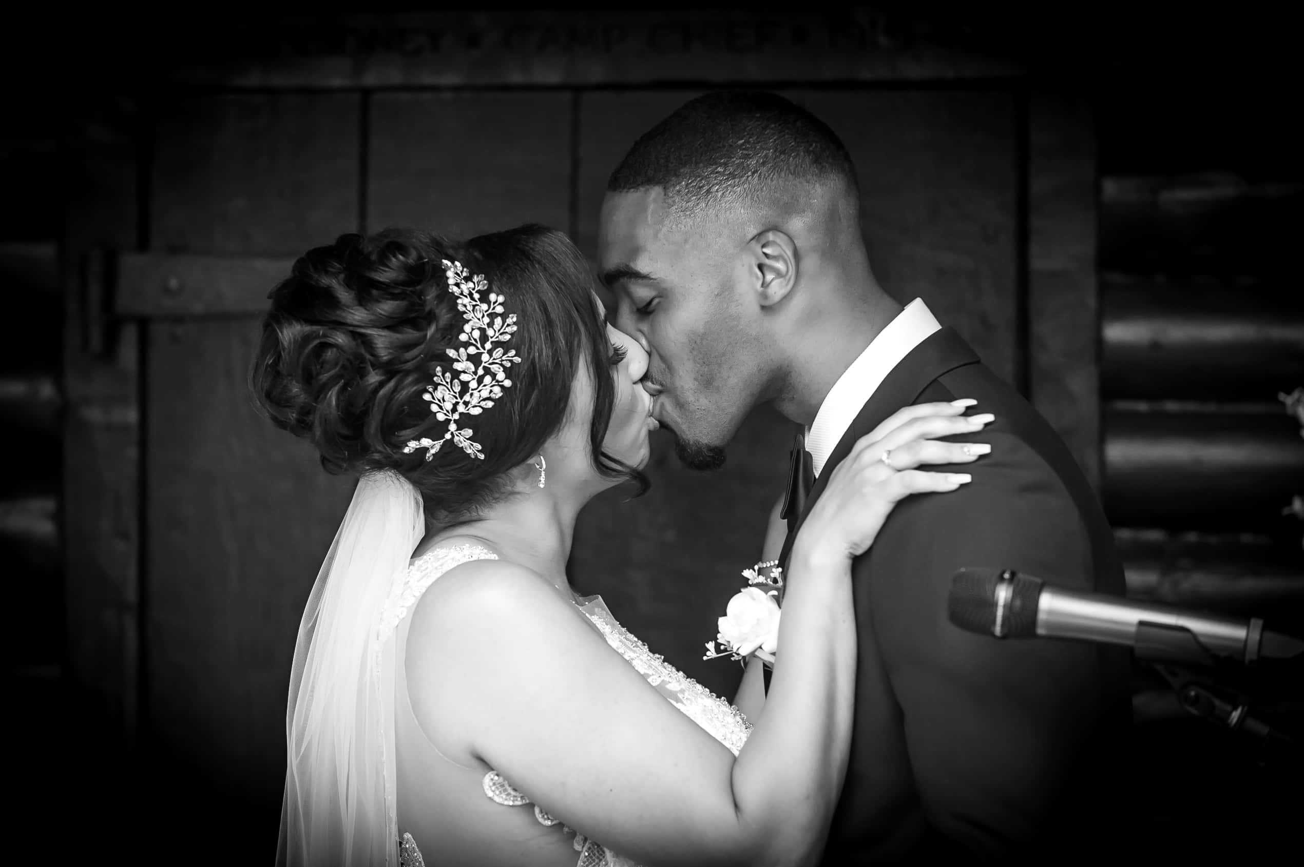 A kiss during the ceremony, in black and white; Joelle and Tashan's wedding at Gilwell, Essex, Lovexposed Photography