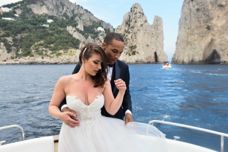 The couple on the deck of a boat off Capri with the Faraglioni behind; styled wedding shoot, Lovexposed Photography