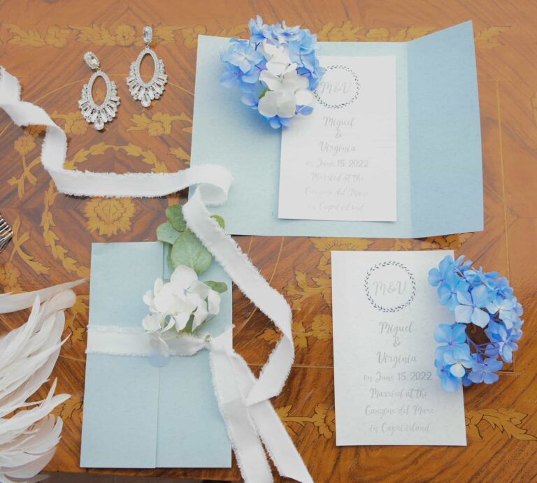 Invitations, ribbon, earrings and blue flowers laid out on the morning of the Capri shoot, Lovexposed Photography