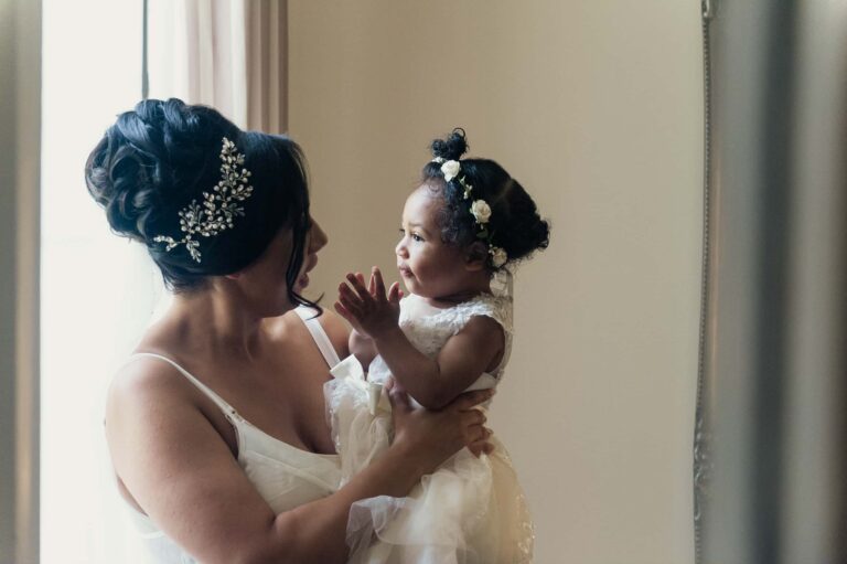 The bride with the youngest flower girl while getting ready; Joelle and Tashan's wedding at Gilwell, Essex, Lovexposed Photography