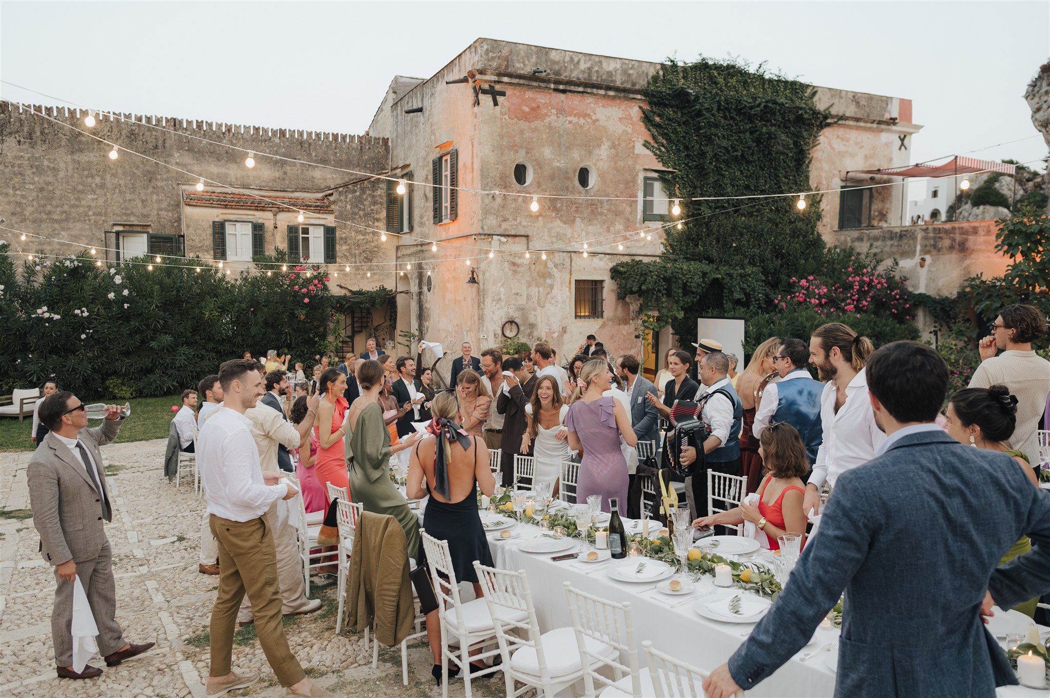 Long reception tables in the tonnara courtyard at Scopello as guests take their seats, LOVIÙ Events