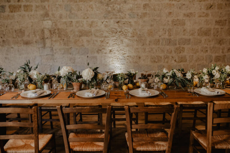 A long table with lemons and greenery against the stone walls of Masseria Susafa, LOVIÙ Events