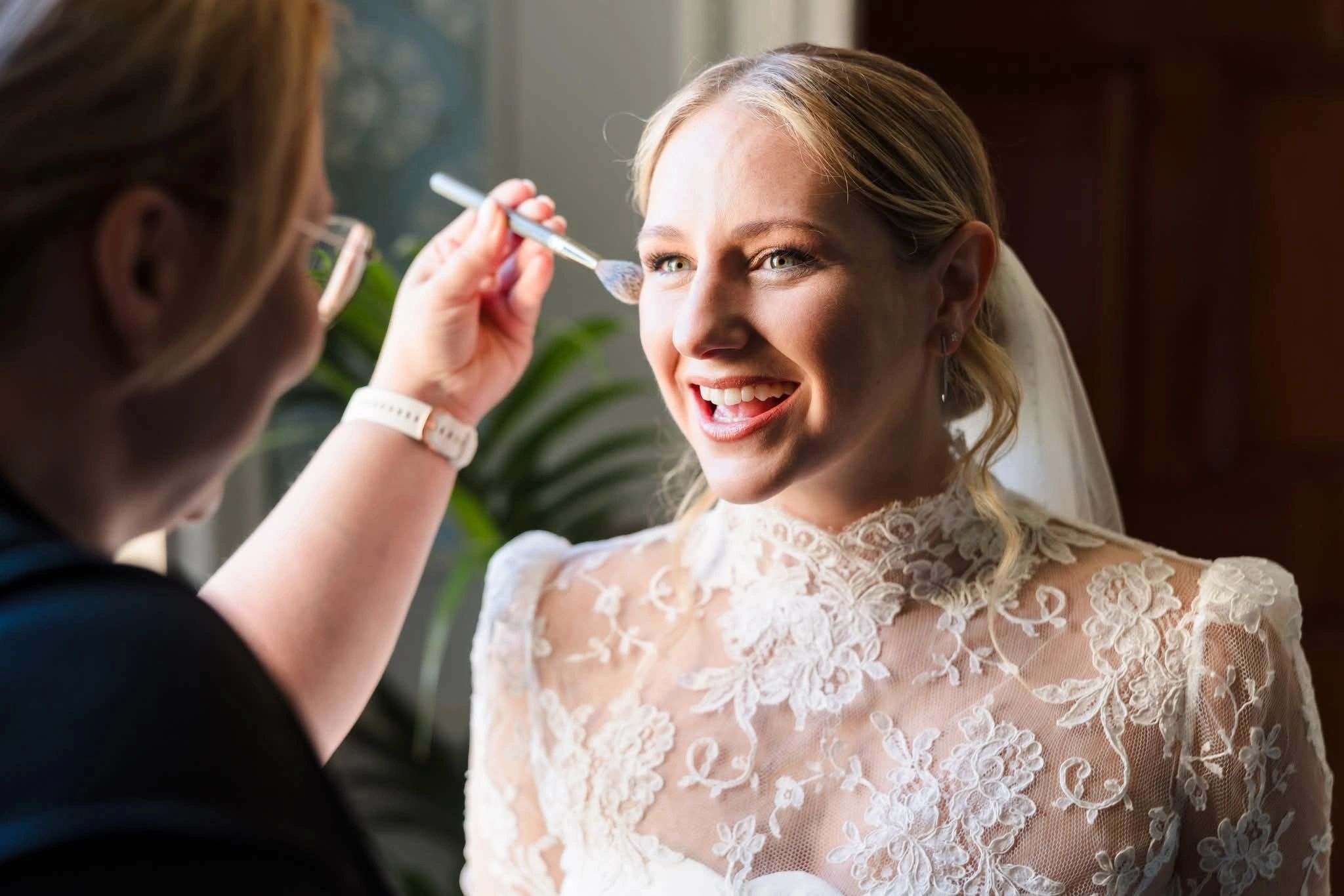 Lip colour applied to a bride in a lace gown, window light behind, Loxus Hair and Makeup
