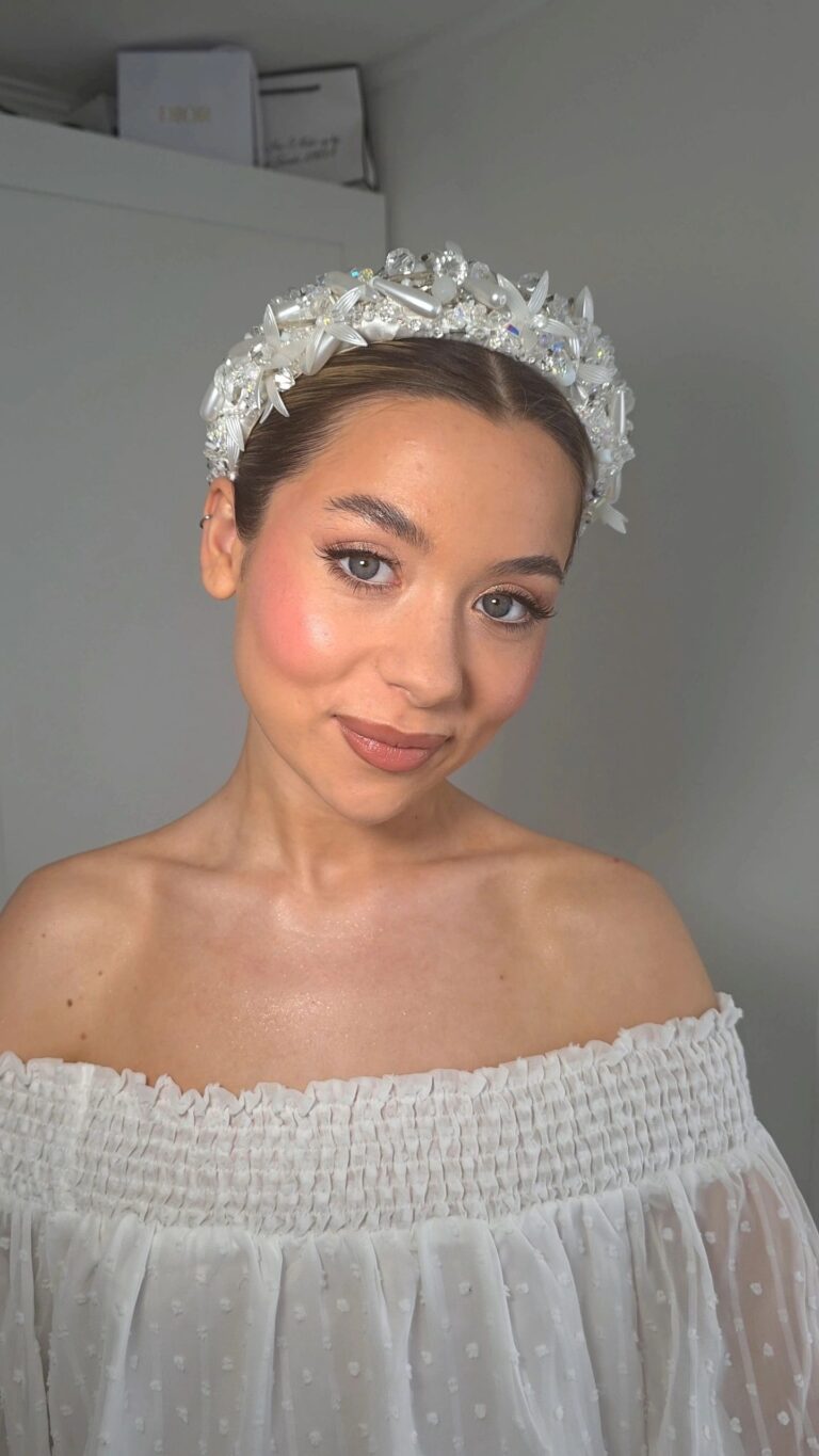 A bride's floral crown and close portrait, an off-the-shoulder top, Loxus Hair and Makeup