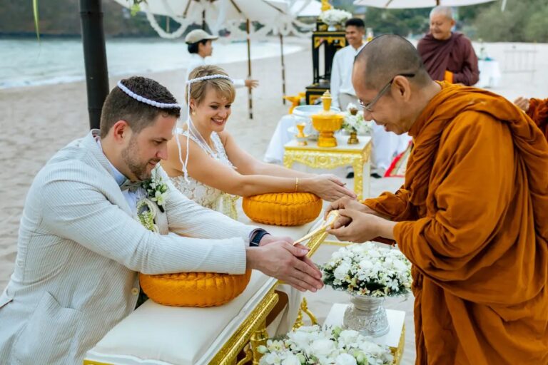 A groom pouring blessed water into a bowl with a monk, bride beside him, Koh Lanta, Lucida Image