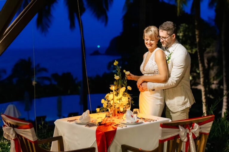 A couple at a candlelit dinner table beneath palm trees at dusk, Koh Lanta, Lucida Image