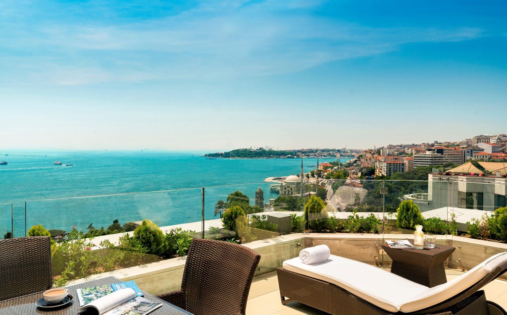 A terrace with loungers and a glass balustrade overlooking the Bosphorus and the city