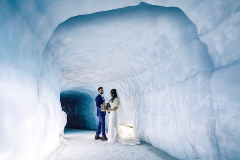 A couple with bouquet inside a glacier ice tunnel lit with pale daylight, Luxwedding Iceland