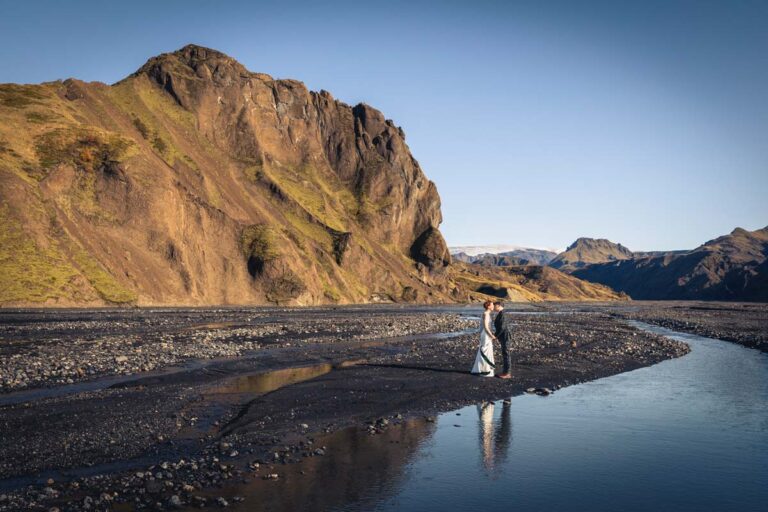 A couple kiss on a black sand river plain below a golden mountain, Luxwedding Iceland