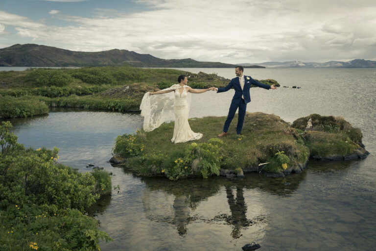 A couple on a small green island in a lake with the bride's veil held out, Luxwedding Iceland