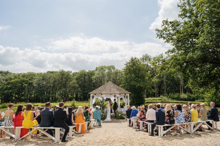 Guests gathered at the gazebo in the grounds for an open-air ceremony by the lake, Lythe Hill Hotel & Spa