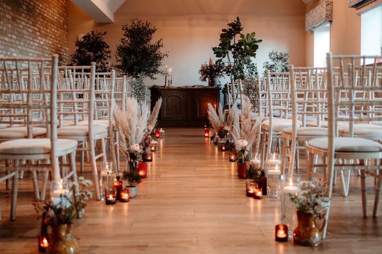 A ceremony aisle lined with candles and chiavari chairs beneath the timbered beams, Lythe Hill Hotel & Spa