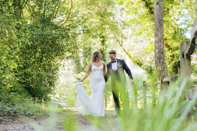 The couple walking a green woodland path in the grounds after the ceremony, Lythe Hill Hotel & Spa