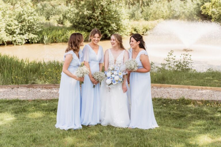 Bridesmaids in pale blue with bouquets on the lawns of the estate, Lythe Hill Hotel & Spa