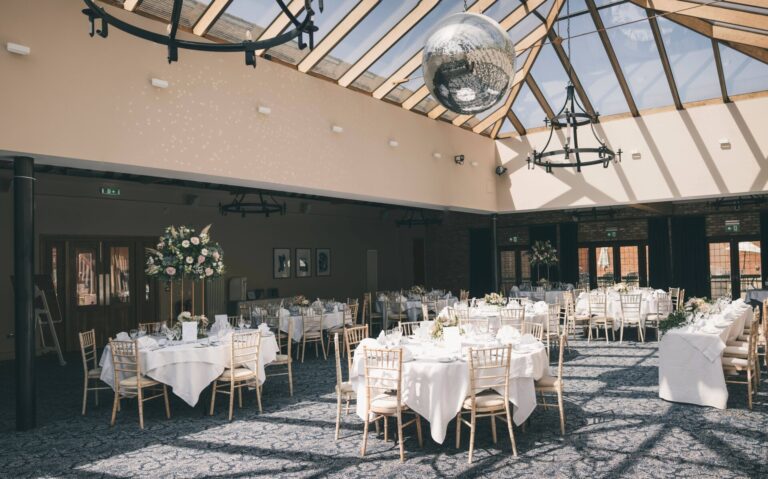 The glass-roofed Ivory Room set with round tables for a daylight wedding breakfast, Lythe Hill Hotel & Spa