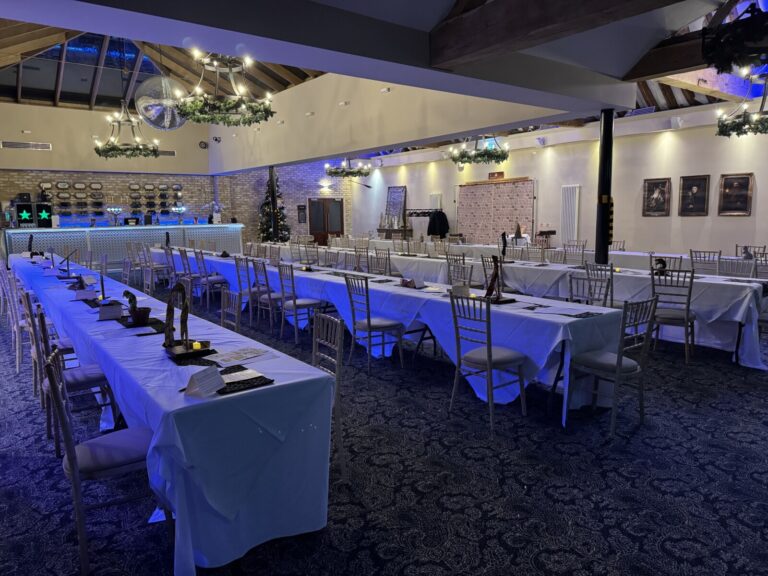 A long banquet table lit in blue for an evening reception in the function room, Lythe Hill Hotel & Spa