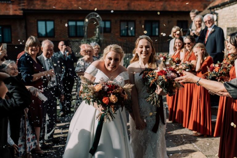 A confetti moment, the bride and groom surrounded by guests in autumn colour, Lythe Hill Hotel & Spa