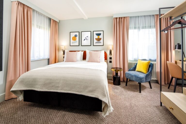A feature bedroom in soft peach tones with a seating corner by the window, Lythe Hill Hotel & Spa